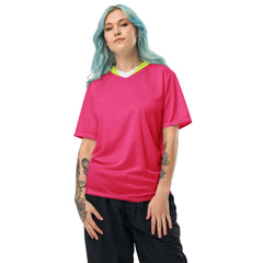 Woman in bold hyper pink V-neck jersey with neon details, showcasing breathable, moisture-wicking fabric for performance.