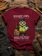 Maroon t-shirt with an owl graphic and text on a wooden surface with work-related items. Night Owl Division warehouse owl wearing a safety vest, holding a barcode scanner and coffee cup, with the slogan When the World Sleeps We Pick.