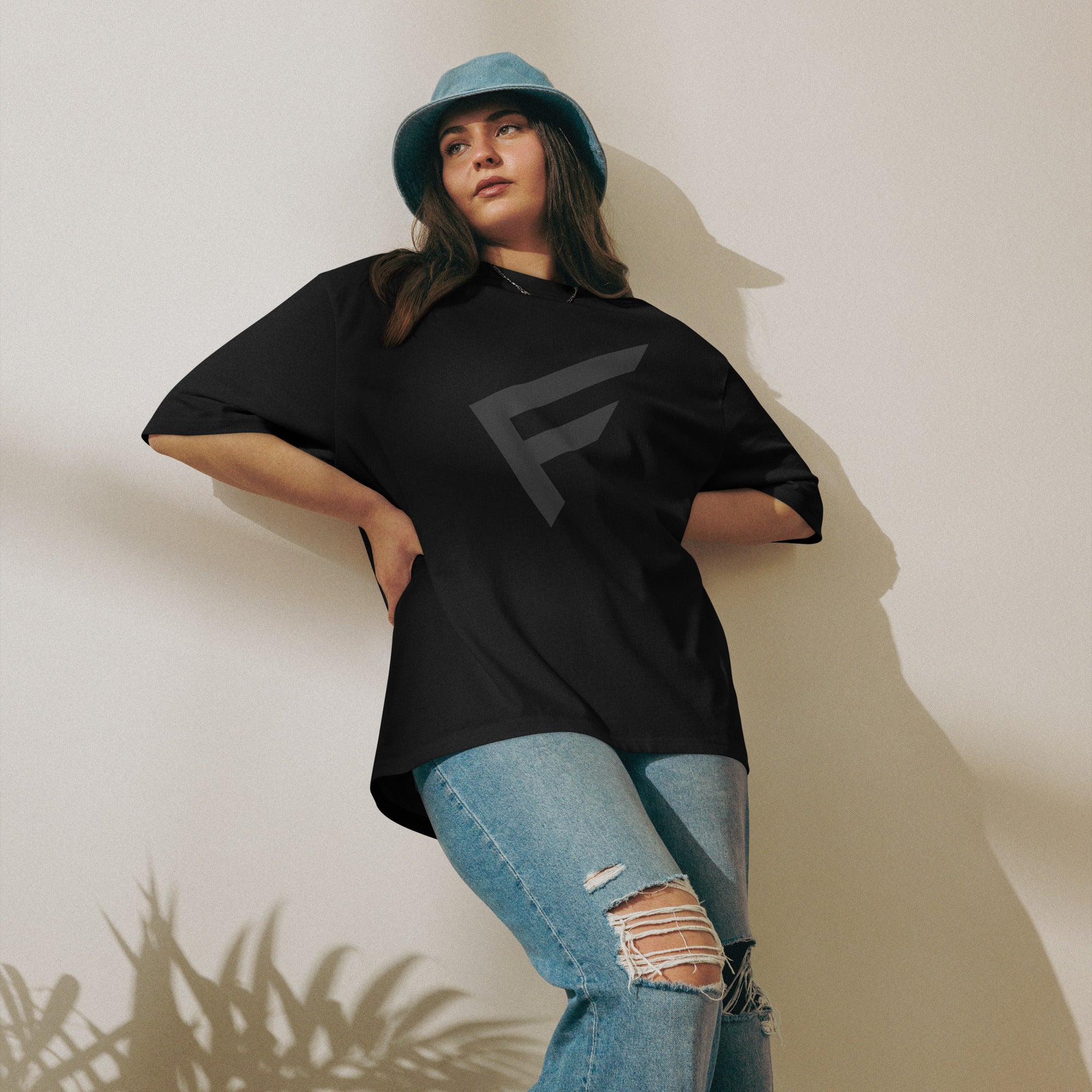 Model wearing the StreetCore Oversized Drop Shoulder Fit tee with a black design, styled with a blue bucket hat.