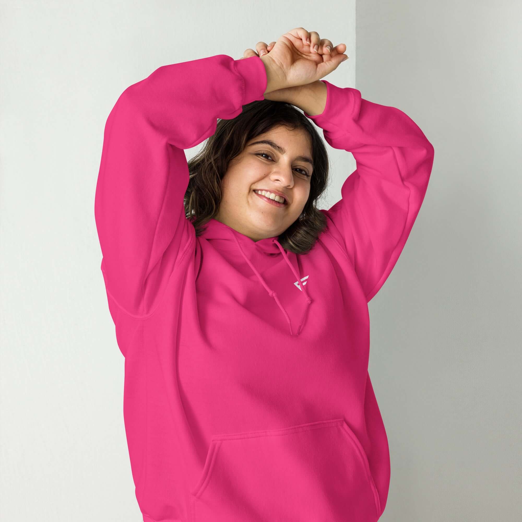 Woman in a vibrant pink hoodie, smiling and celebrating everyday comfort in fashionable loungewear.