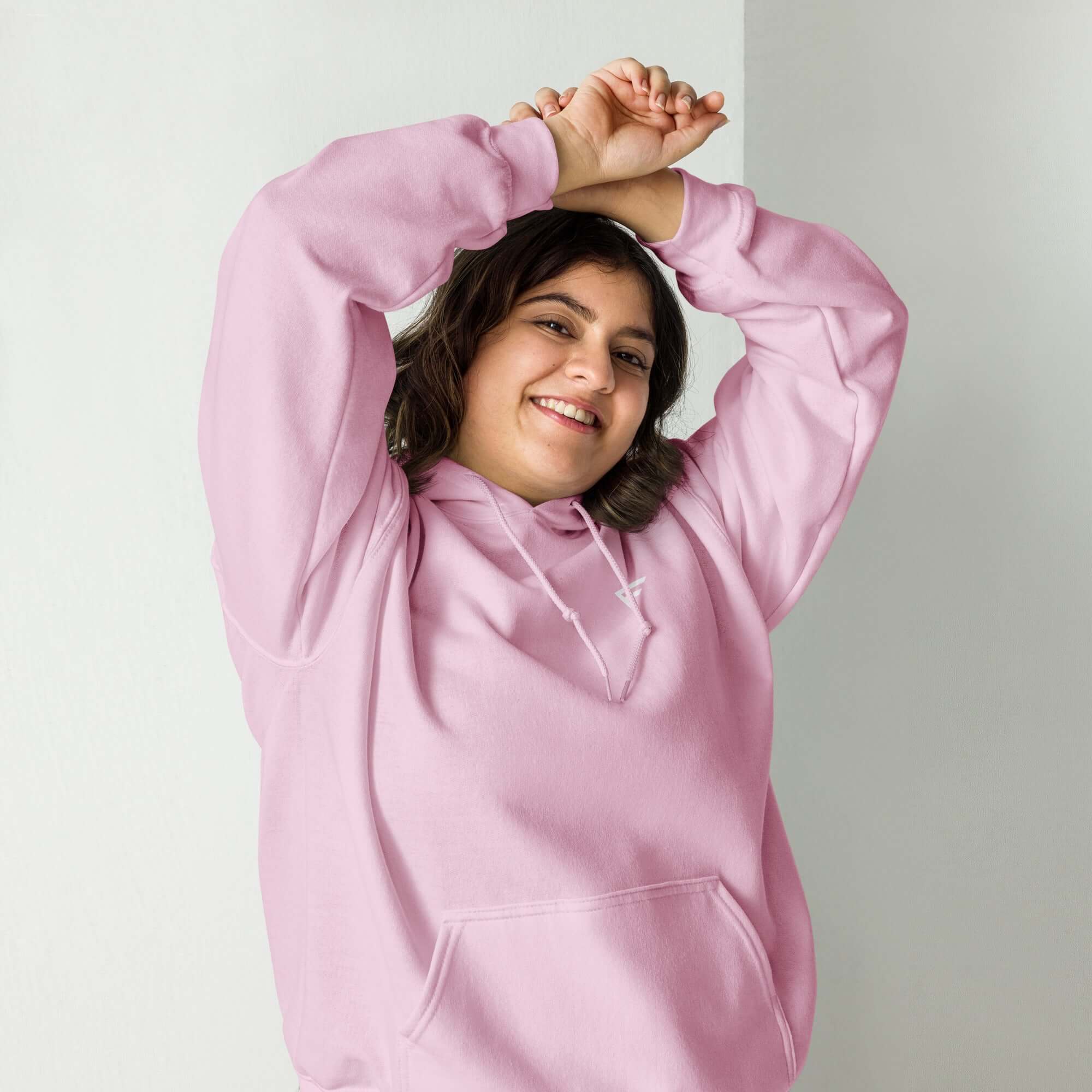 Smiling woman wearing a soft pastel pink hoodie, showcasing comfort and style for everyday wear.